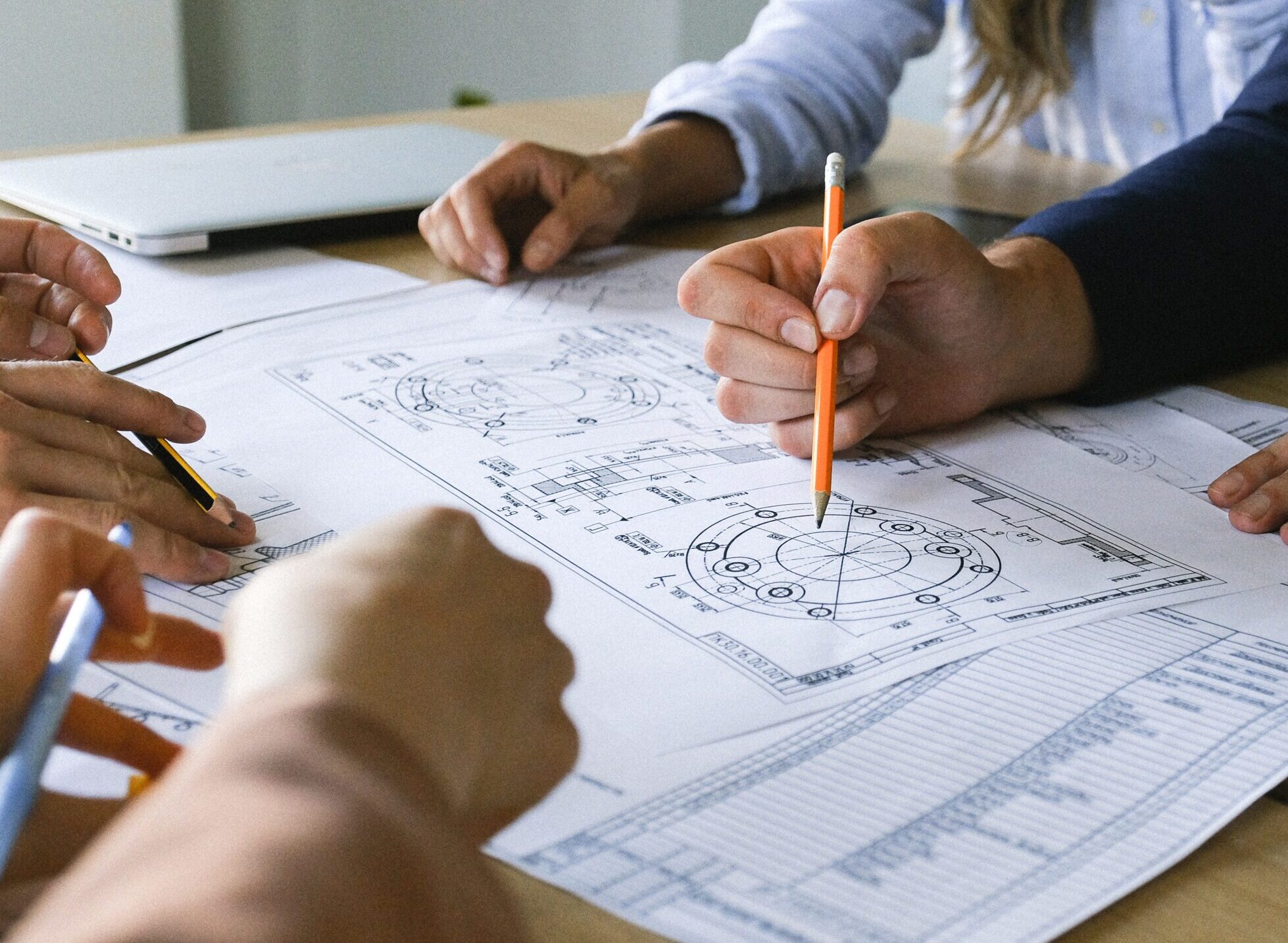 people sitting around a table discussing and writing on building plans
