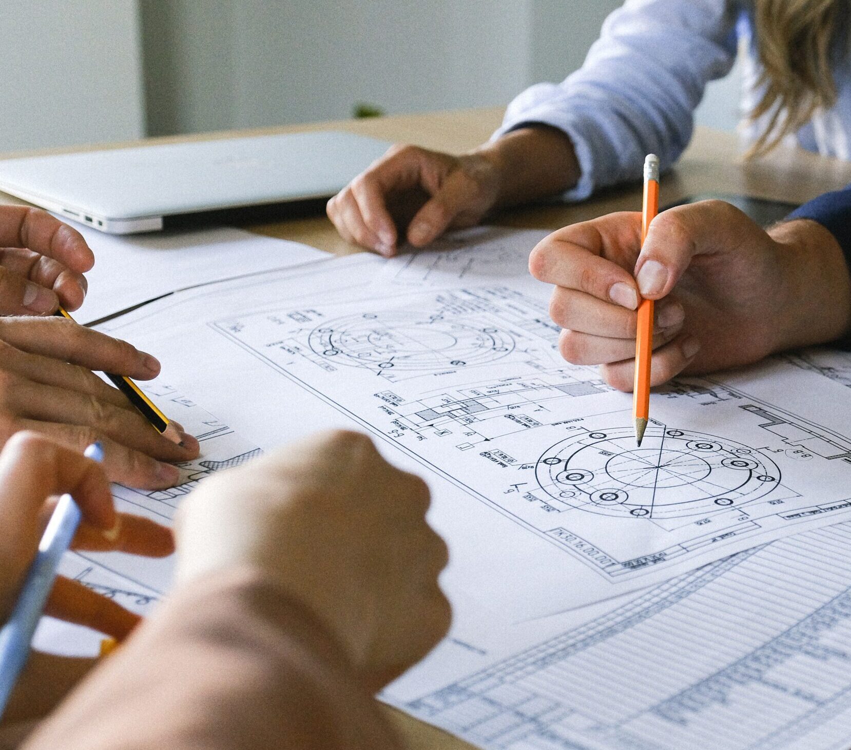 a group of people looking over and marking notes on schematics